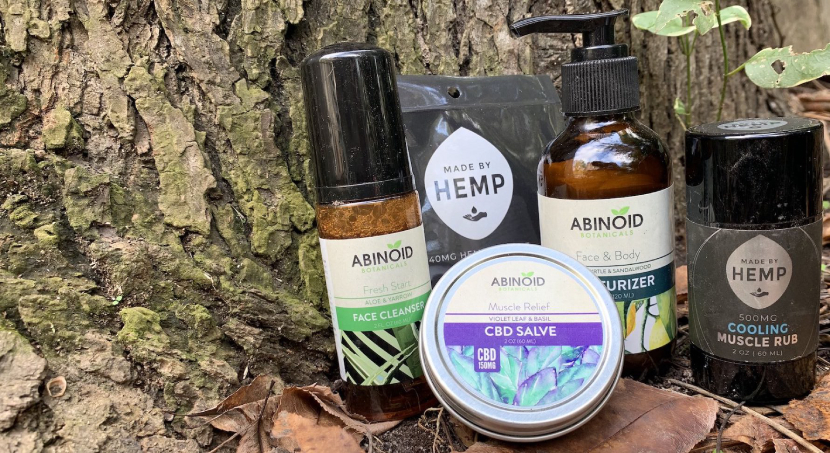 Abinoid and Made By Hemp CBD Products on a tree stump